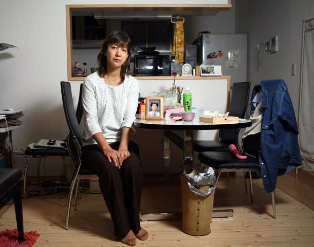 Hiroko Uchino in her home in Aichi, Japan, with a picture of her late husband, Kenichi, 30, a quality control officer at Toyota, who died at his office. Uchino wanted a government labour agency to legally recognize that he had died from overwork, something so common that there is a Japanese word for it, karoshi.