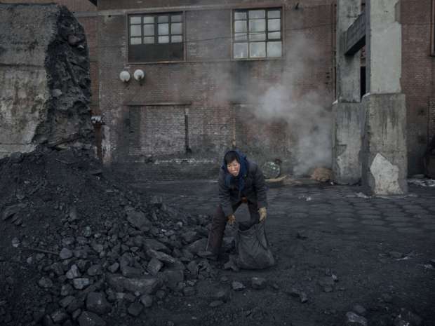 A Chinese woman collects coal in a sorting area at a coal mine on November 25, 2015 in Shanxi, China. Chinese officials have started discouraging coal use.