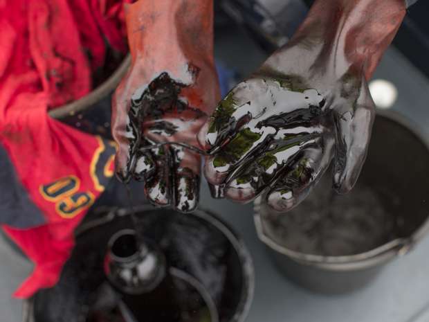 Refined oil sits on a a crew member's gloves on board an oil tanker barge. After watching prices crash through floor after floor in the worst slump for a generation, the oil industry is eager for answers.