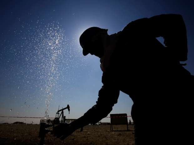 An oil worker adjusts a valve releasing a spray of water while working on oil pipelines Thursday in the Middle East.