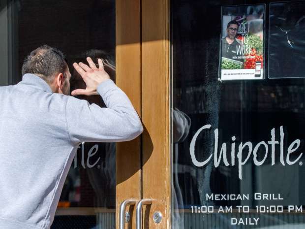 A man looks through the locked front door of a Chipotle restaurant