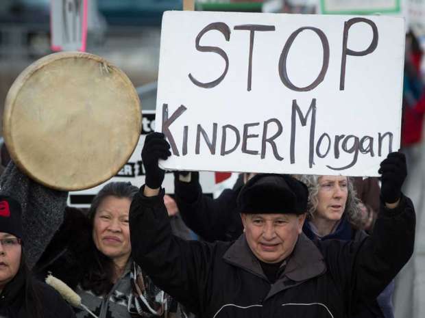 Grand Chief Stewart Phillip, president of the Union of B.C. Indian Chiefs, holds a sign while marching to a protest outside National Energy Board hearings on the proposed Trans Mountain pipeline expansion in Burnaby, B.C., on Tuesday January 19, 2016.